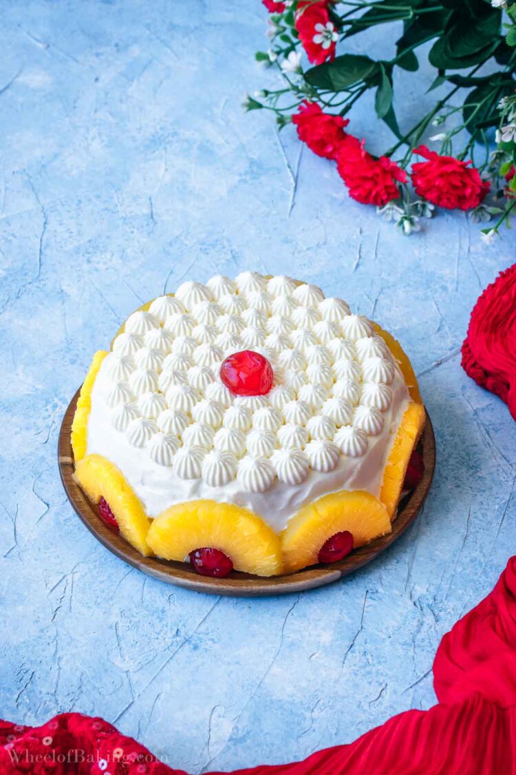 Pineapple cream cake decorated with pineapple slices and candied cherries.